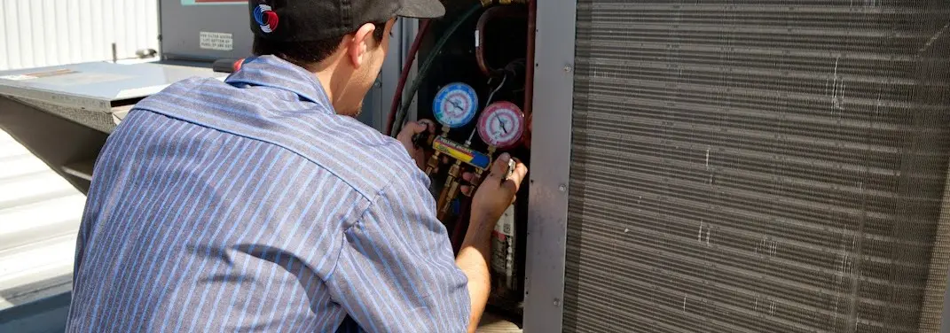 HVAC technician servicing a condenser unit in Wolcott