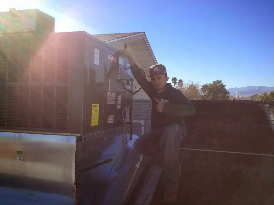 HVAC technician performing Heat Pump Repair on a rooftop unit in Wolcott
